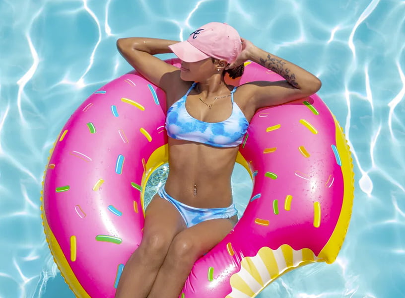 a young woman lounging in a pool in a pink donut intertube