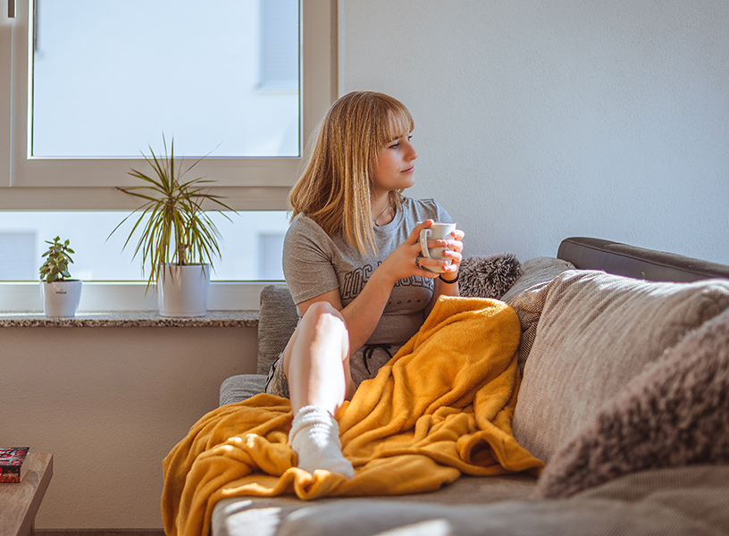 Young woman enjoying a cup of coffee while relaxing on the couch