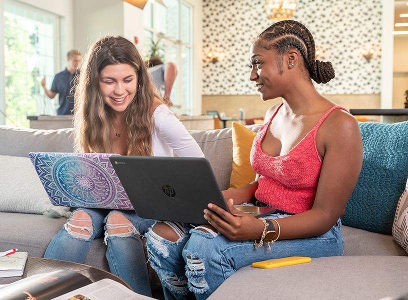 Two young residents studying on laptops together